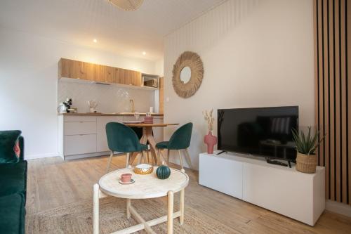 a living room with a television and a table and chairs at Bel appartement neuf en plein centre in Brantôme