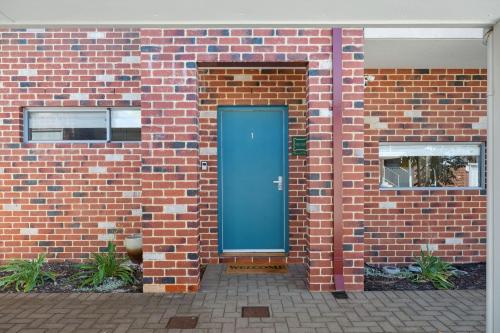 a blue door on the side of a brick building at Happy Stays Classic Mid-Century Modern Escape in Perth
