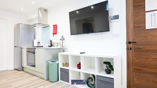 a kitchen with a refrigerator and a tv on a wall at Old Silk Apartments - Luxury Studios, 1 & 2-beds in Coventry City Centre by COVSTAYS in Coventry