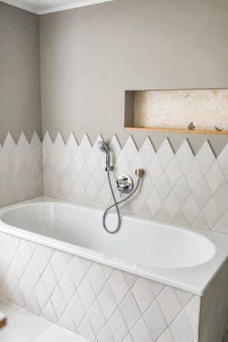 a bath tub in a bathroom with white tiles at Biohotel Gralhof in Weissensee