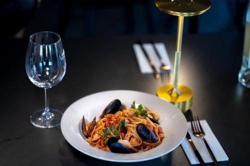 a plate of pasta with mussels and a wine glass at Pension Bella Vista in Sighişoara