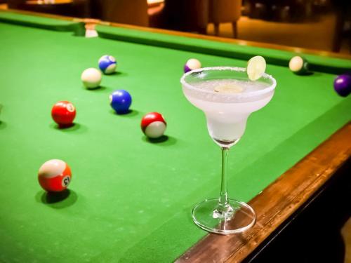 a martini glass on a pool table with pool balls at Lemon Tree Hotel Whitefield, Bengaluru in Bengaluru