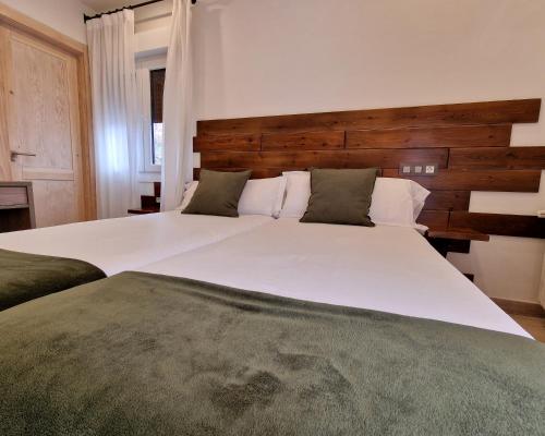 a bedroom with two white beds and a wooden headboard at Hostal Remoña in Espinama