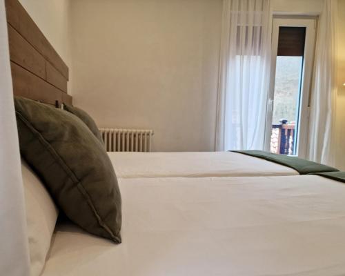 a bedroom with a bed with white sheets and a window at Hostal Remoña in Espinama