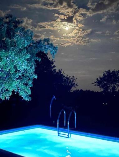 a swimming pool at night with the moon in the sky at trullo fino in Cisternino