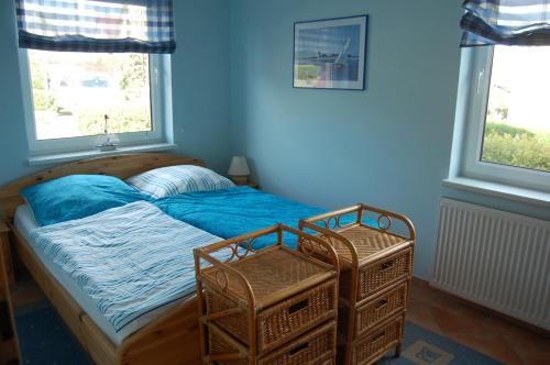 a bedroom with a bed with blue sheets and two windows at Gästehaus am Fischerweg in Lauterbach