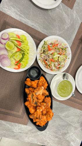 a table with three plates of food on it at Golden GSC Hotel in Amritsar