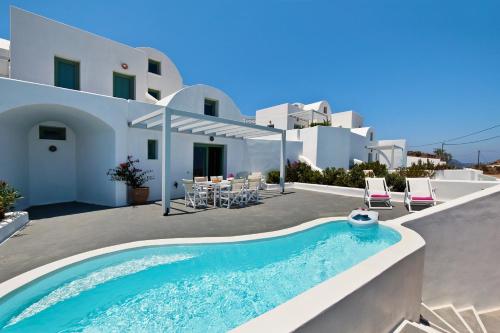 a villa with a swimming pool in front of a house at Aura Marina Apartments Santorini in Akrotiri