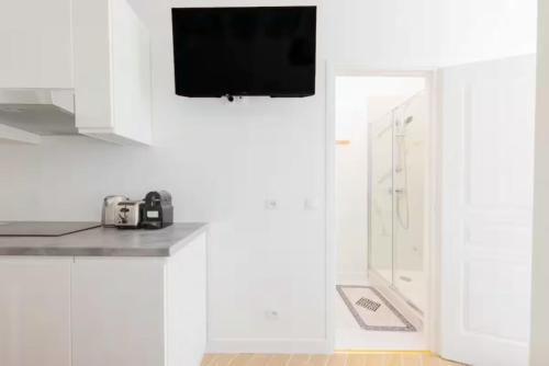 La salle de bains est pourvue d'armoires blanches et d'une télévision murale. dans l'établissement Charming apartment near Gare de l'Est, à Paris