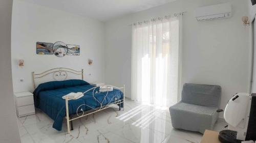 a white bedroom with a blue bed and a chair at Clarus Mons in Chiaromonte
