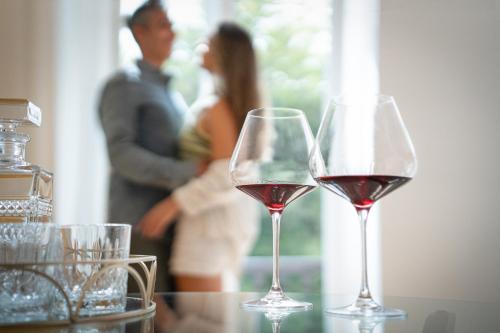 two glasses of wine on a table with a man and a woman at Guesthouse diWINE in Merano