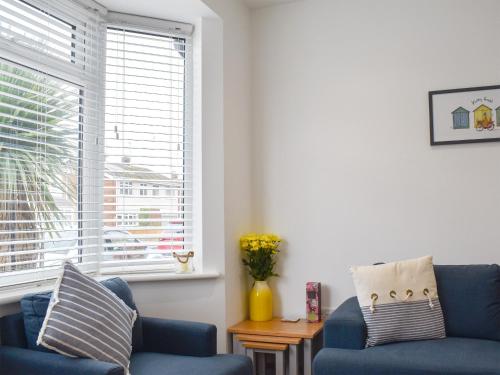 a living room with two blue chairs and a window at Sapphire Cottage in Lowestoft