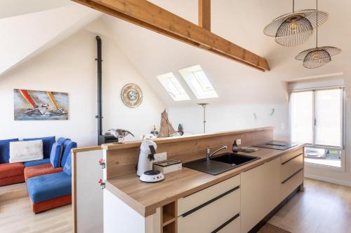 une cuisine avec des placards blancs et une chaise bleue dans l'établissement L'Abri Côtier d'Argäe - Terrasse vue mer, à Erquy