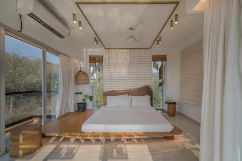 a bedroom with a bed and a large window at SaffronStays Nautica in Harnai