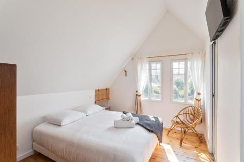 Un dormitorio blanco con una cama y una silla. en Les Bulles d'Or - A 400m de la plage, en Fréhel