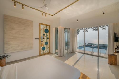a bedroom with a bed and large windows and a pool at SaffronStays Nautica in Harnai
