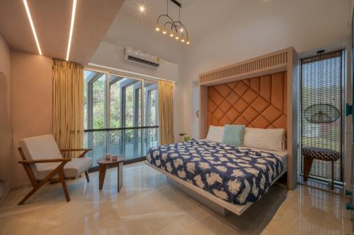 a bedroom with a bed and a table and a chair at SaffronStays Nautica in Harnai