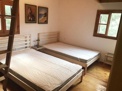 two beds in a room with two windows at Reina's house by the sea in Akti Salonikiou