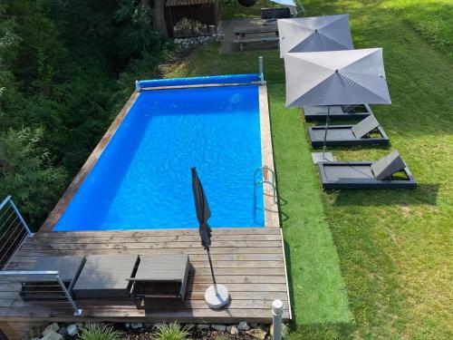 einen Blick über einen Pool mit Sonnenschirm in der Unterkunft Sportives Ökologisches Lifestyle-Ferienhaus mit großem Außenpool, Sauna und Fitnessbereich in Donaueschingen