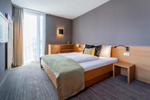 a bedroom with a bed and a large window at Ritzenhof - Hotel und Spa am See 4-Sterne-Superior in Saalfelden am Steinernen Meer
