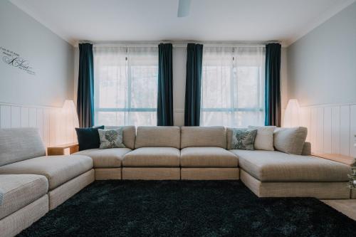 a living room with a couch and two windows at Retreat, Relax, Repeat in Katoomba, Blue Mountains in Katoomba