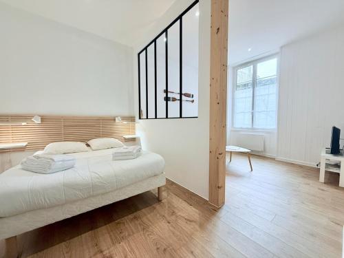 une chambre blanche avec un lit et une grande fenêtre dans l'établissement 1738 - T1 Bis Corderie Royale RDC hyper Centre, à Rochefort