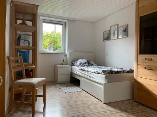 a bedroom with a bed and a chair and a window at Zu Gast bei Freunden in Weingarten (Karlsruhe)
