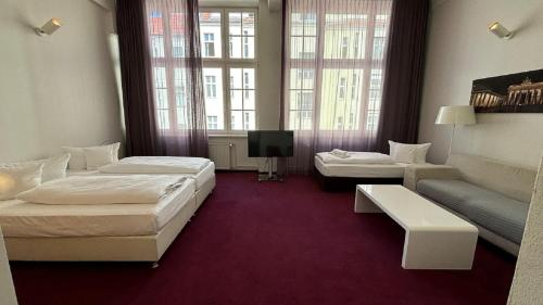a hotel room with two beds and a couch at Wyndham Garden Berlin Mitte in Berlin