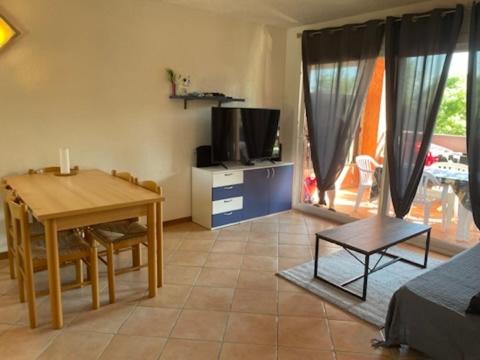 ein Wohnzimmer mit Tisch und Fernseher und ein Esszimmer in der Unterkunft LES BULLES DE MONA - Marina Corse - 2 ch - Clim - Terrasse-pieds dans leau-plage in Ghisonaccia