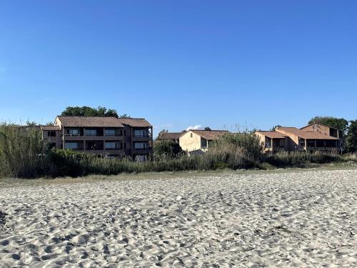 ein Gebäude am Strand mit Häusern im Hintergrund in der Unterkunft LES BULLES DE MONA - Marina Corse - 2 ch - Clim - Terrasse-pieds dans leau-plage in Ghisonaccia
