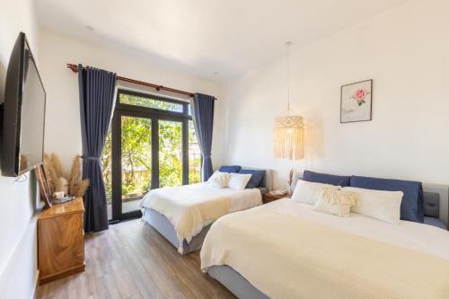 a bedroom with two beds and a tv and a window at Boho Boutique Da Lat - View nhà lồng lãng mạn in Da Thanh
