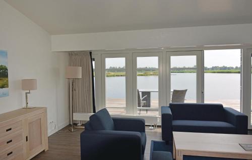 ein Wohnzimmer mit blauen Stühlen und Blick aufs Wasser in der Unterkunft Bodelaeke-Rietwoning in Giethoorn