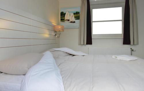 ein weißes Bett in einem Zimmer mit Fenster in der Unterkunft Bodelaeke-Rietwoning in Giethoorn