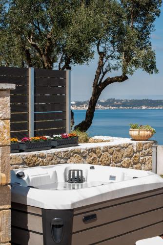 a white bath tub sitting next to a stone wall at Coral Summer Lux Cottage in Argassi