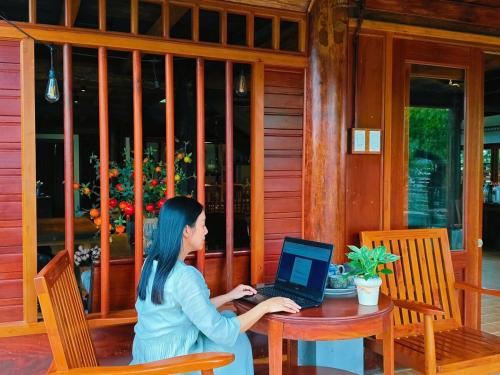 a woman sitting at a table with a laptop at Moc Homestay & Villa in Cư Chinh