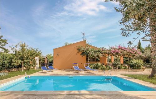 a pool in front of a house with chairs and a building at Villa Esmeralda in Menfi
