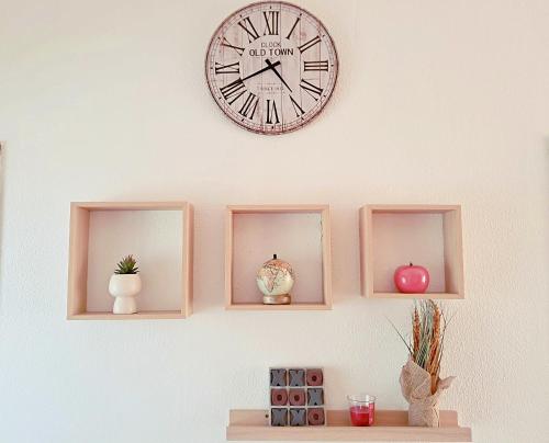 a clock hanging on a wall with three shelves at Apartamento Alvor in Alvor