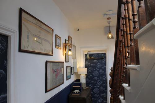 a hallway with a staircase with pictures on the wall at The Old Buoy Inn in Seahouses