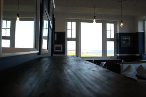 a large wooden table in a room with windows at The Old Buoy Inn in Seahouses