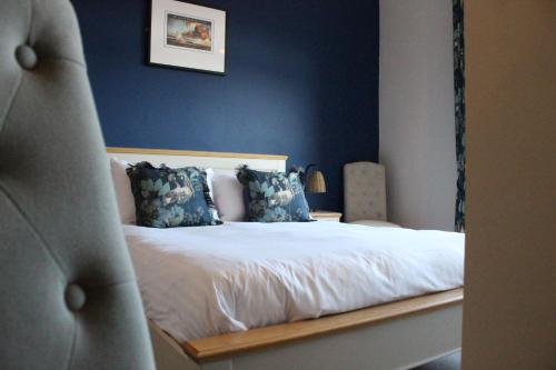 a bedroom with a white bed with blue walls at The Old Buoy Inn in Seahouses