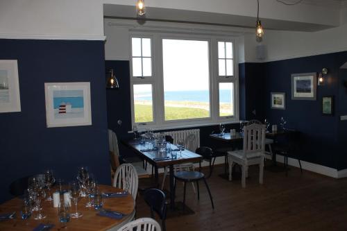 a dining room with tables and chairs and a window at The Old Buoy Inn in Seahouses