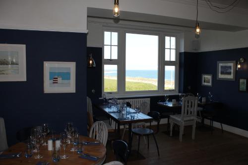 a dining room with tables and chairs and a window at The Old Buoy Inn in Seahouses