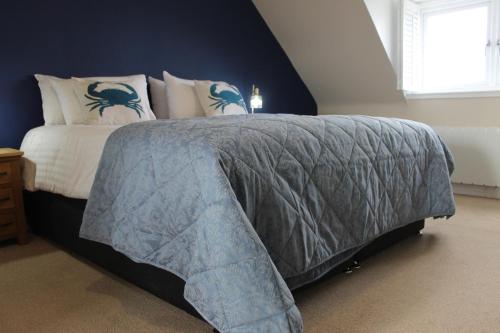 a bedroom with a bed with a blue wall at The Old Buoy Inn in Seahouses