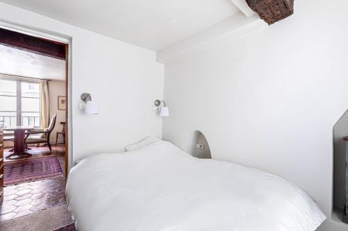 une chambre blanche avec un lit et une table dans l'établissement GuestReady - Discover the Charm of Paris, à Paris