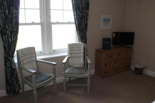 two chairs and a television in a room with a window at The Old Buoy Inn in Seahouses