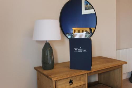 a mirror and a vase on a table with a lamp at The Old Buoy Inn in Seahouses