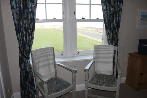 two white chairs sitting in front of a window at The Old Buoy Inn in Seahouses