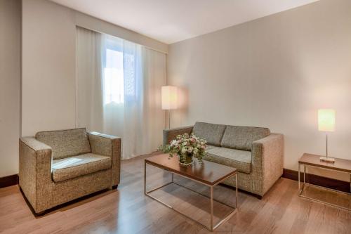 a living room with two chairs and a couch and a table at NH Campo de Gibraltar in Los Barrios