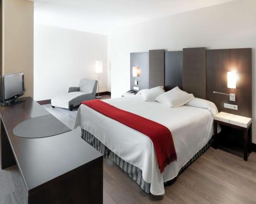 a hotel room with a large bed and a tv at NH Campo de Gibraltar in Los Barrios