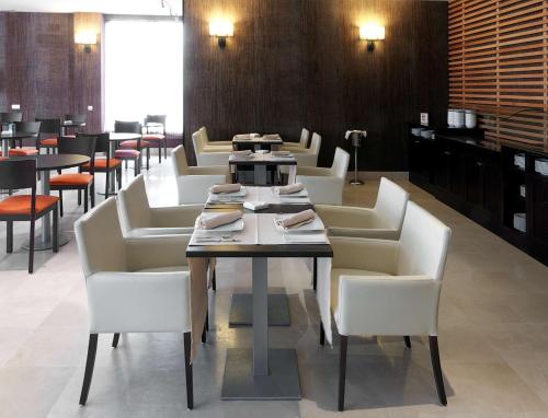 a dining room with a table and white chairs at NH Campo de Gibraltar in Los Barrios